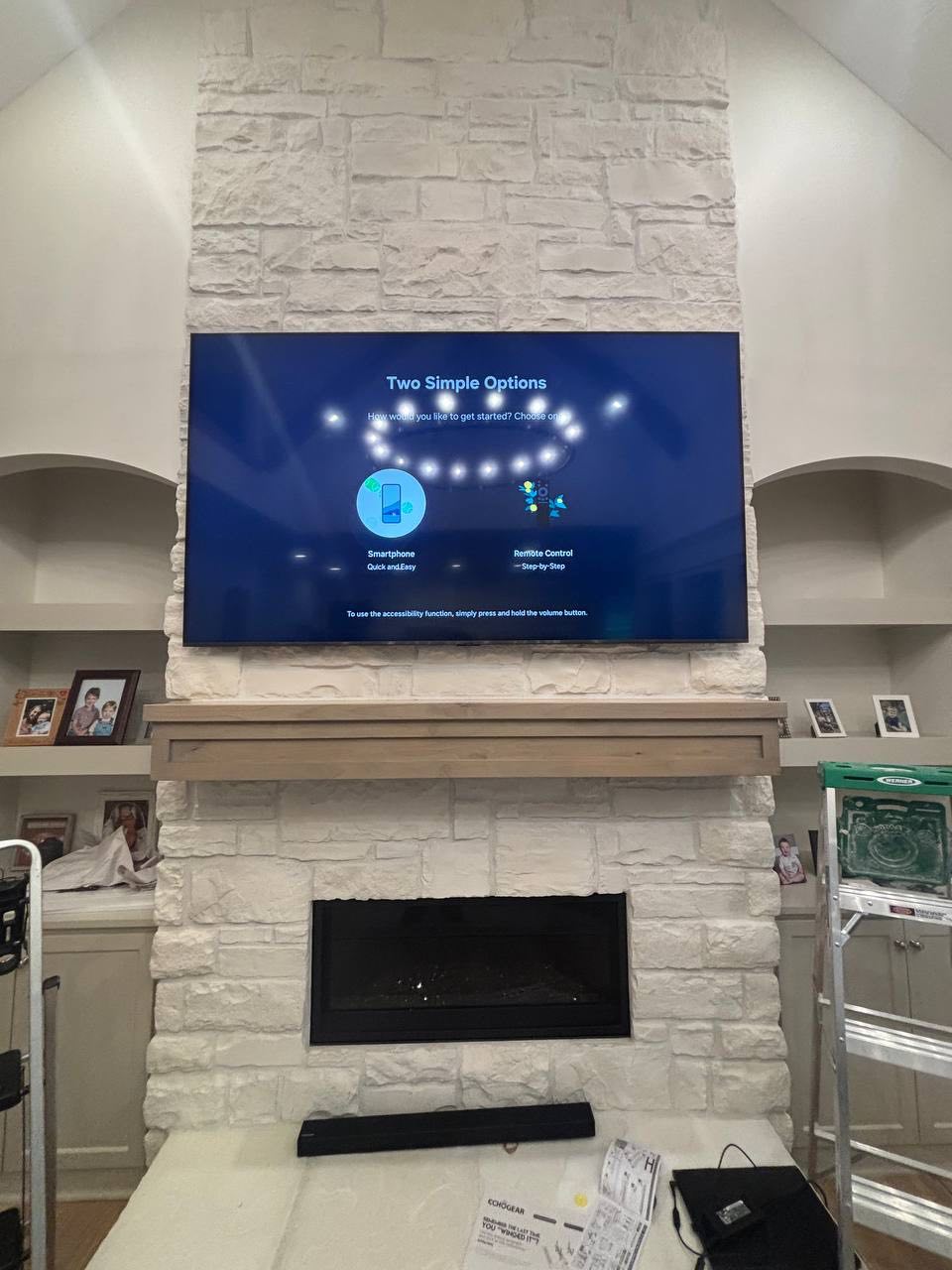 Large television installed above a stone fireplace